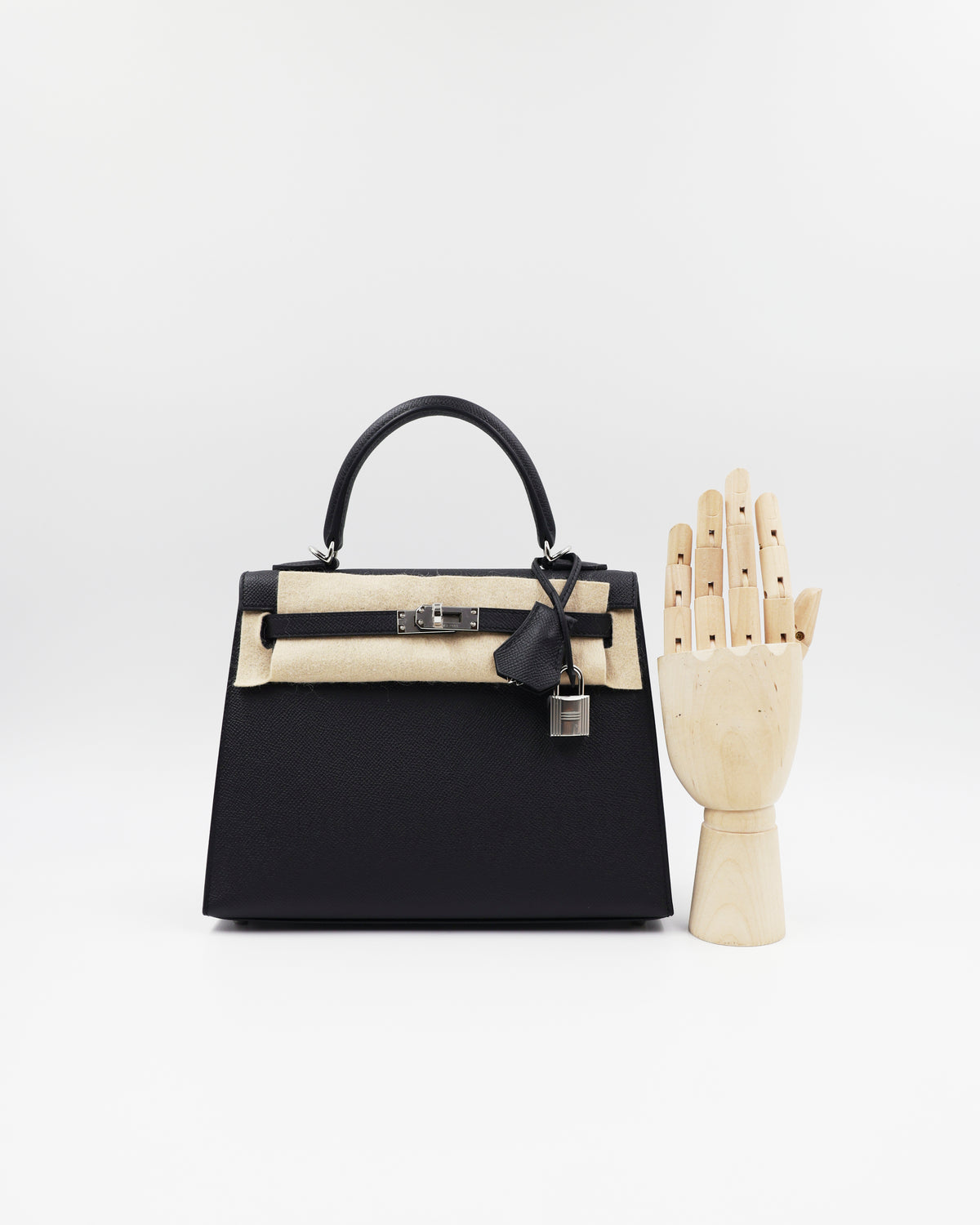 HERMÈS Kelly 25 Sellier Epsom schwarz PHW als schwarze Designerhandtasche mit Handmodell