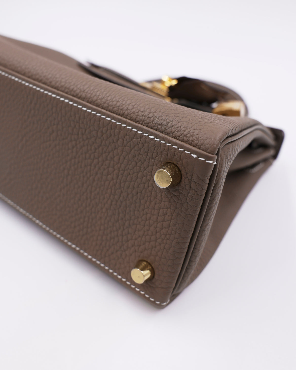 HERMÈS Kelly 25 Togo Etoupe GHW Unterseite einer taupefarbenen Designerhandtasche mit goldfarbenen Beschlägen