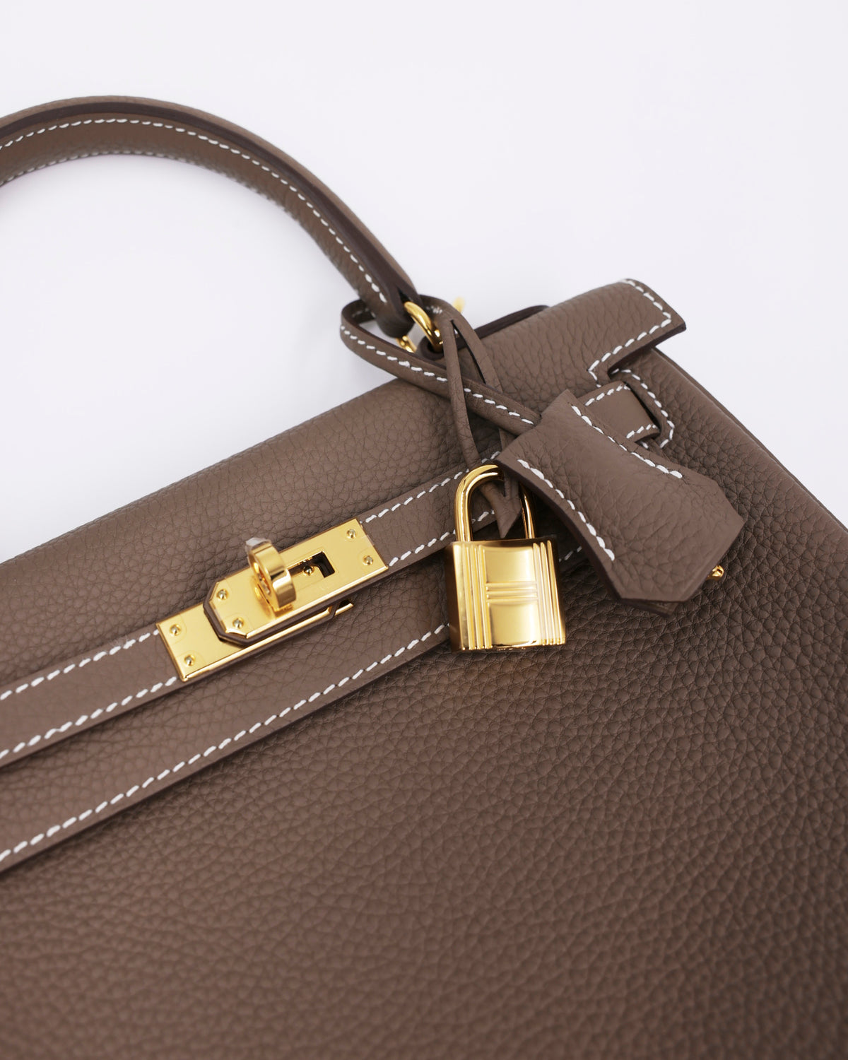 Detailansicht HERMÈS Kelly 25 Togo Etoupe GHW mit goldfarbenem Schloss und strukturierter Oberfläche