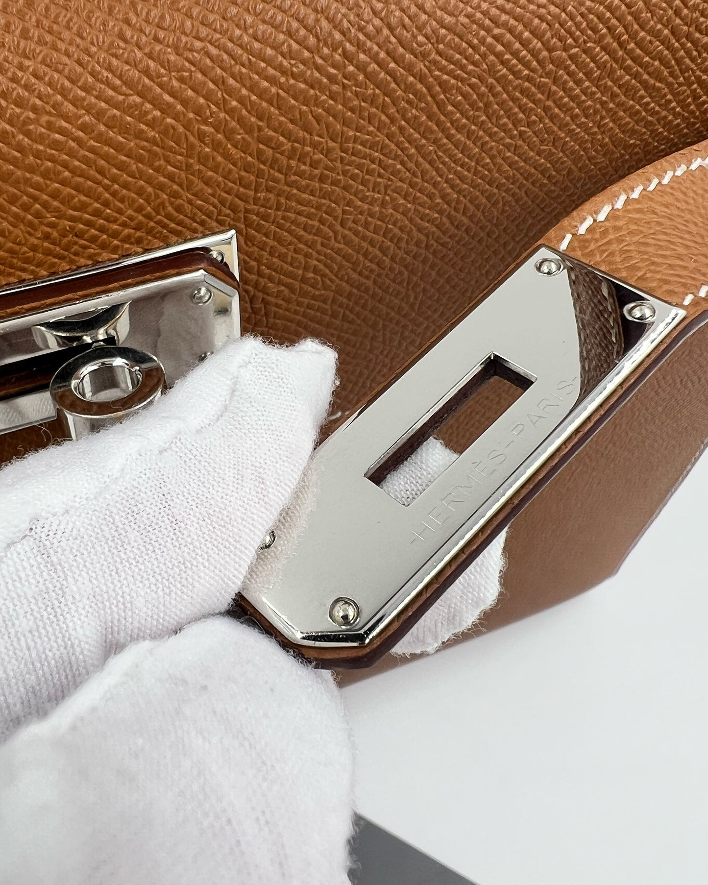 Detailaufnahme der HERMÈS Kelly 28 Epsom Sellier Gold PHW inklusive Twilly mit Verschluss und Lederstruktur