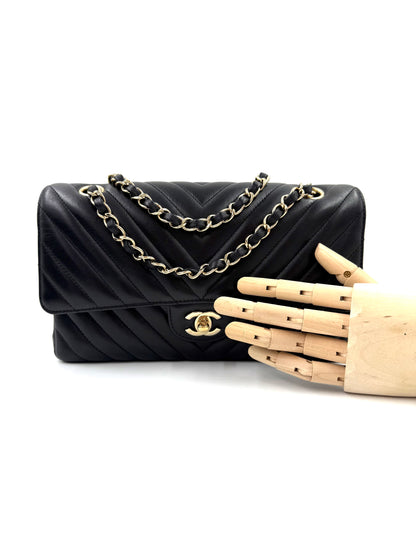 CHANEL Timeless Double Flap medium Chevron schwarz aus schwarzem Leder mit goldfarbener Kette und CC-Verschluss.