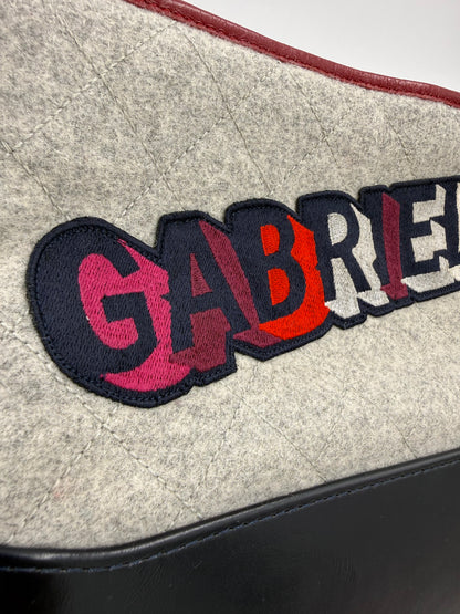 CHANEL Gabrielle medium dunkelblau Nahaufnahme des gesteppten Filzes mit farbigem Logo und schwarzer Lederkante
