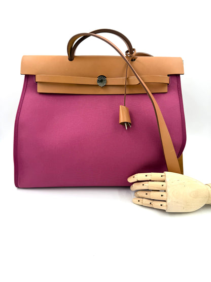 HERMÈS Herbag 39 Zip pink mit braunem Lederbesatz und verstellbarem Schulterriemen vor weißem Hintergrund