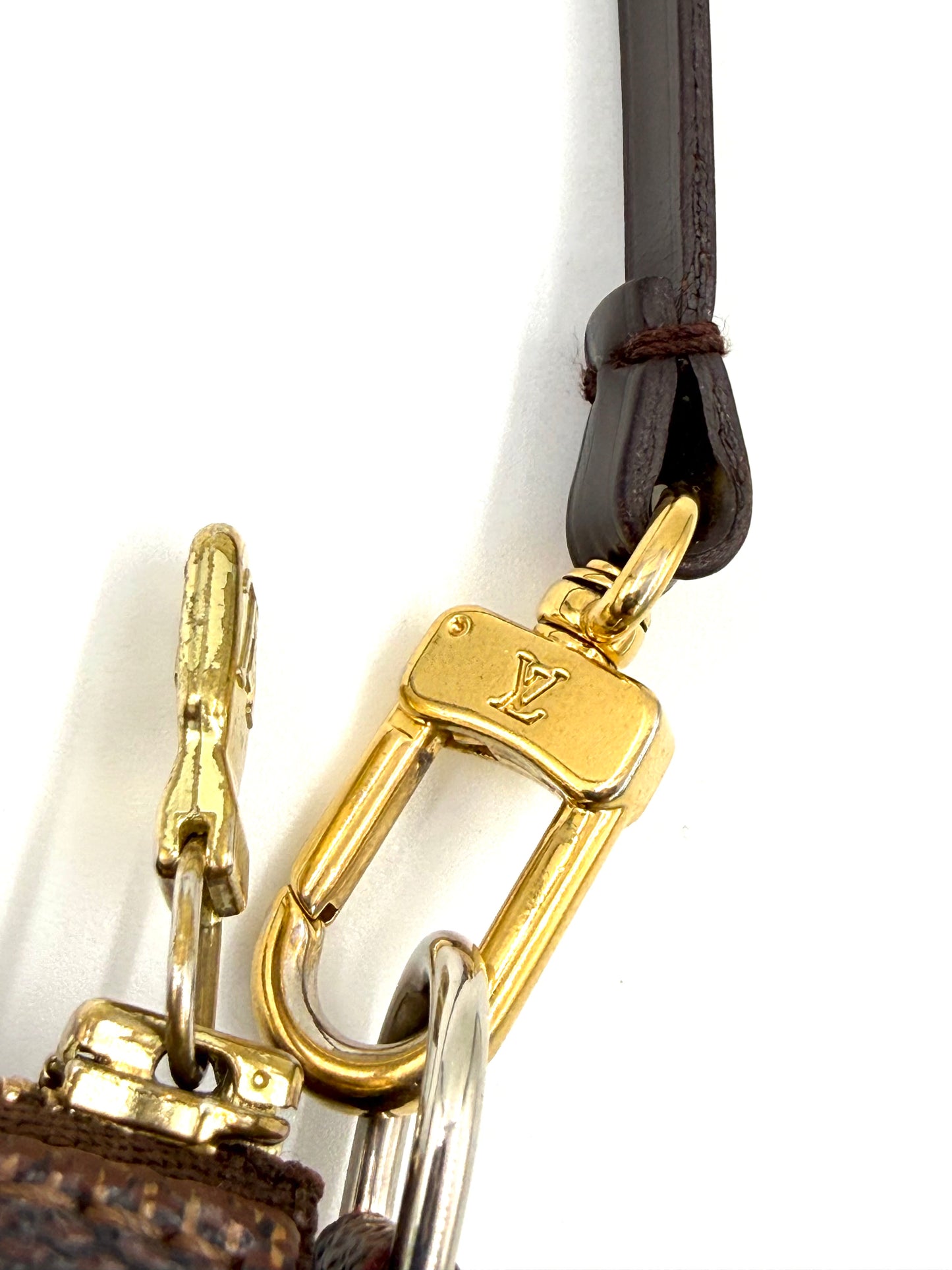 Goldfarbener Karabiner mit LV-Logo an dunkelbraunem Lederband der LOUIS VUITTON Pochette Accessoires Damier Ebene Tasche.