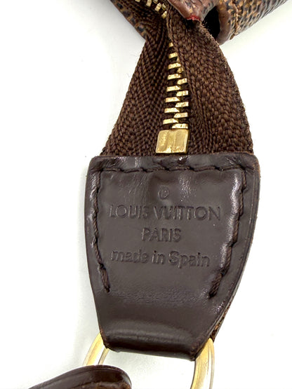 Nahe Aufnahme des Lederlabels mit Prägung von LOUIS VUITTON Pochette Accessoires Damier Ebene aus braunem Canvas und Leder.