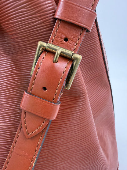 Detailaufnahme eines verstellbaren Lederriemens mit Metallschnalle der LOUIS VUITTON Noe grande Epi kenian Tasche.