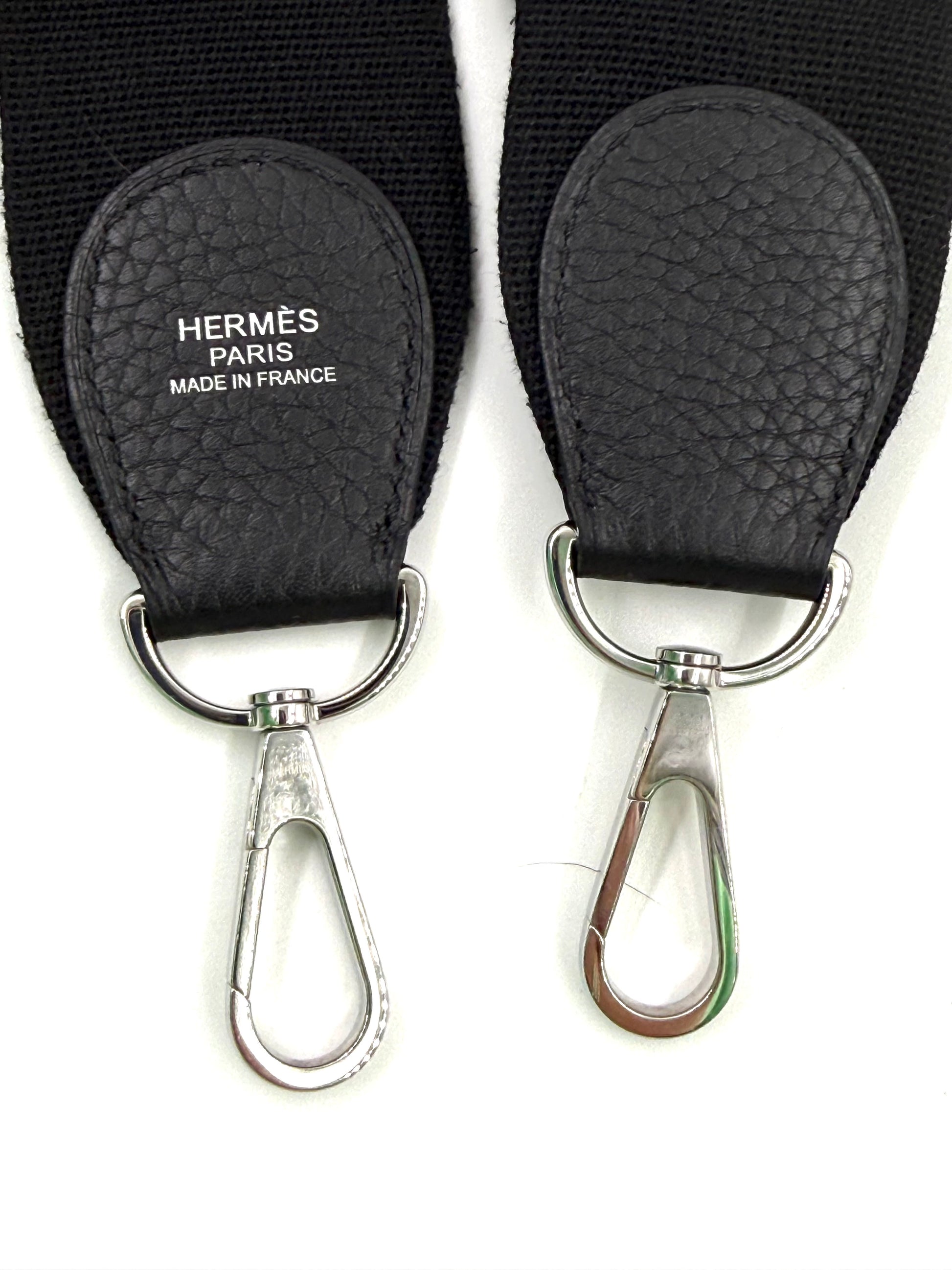 Detailaufnahme der Metallkarabiner und Lederriemen der HERMÈS Evelyne 29 schwarz PHW Designerhandtasche