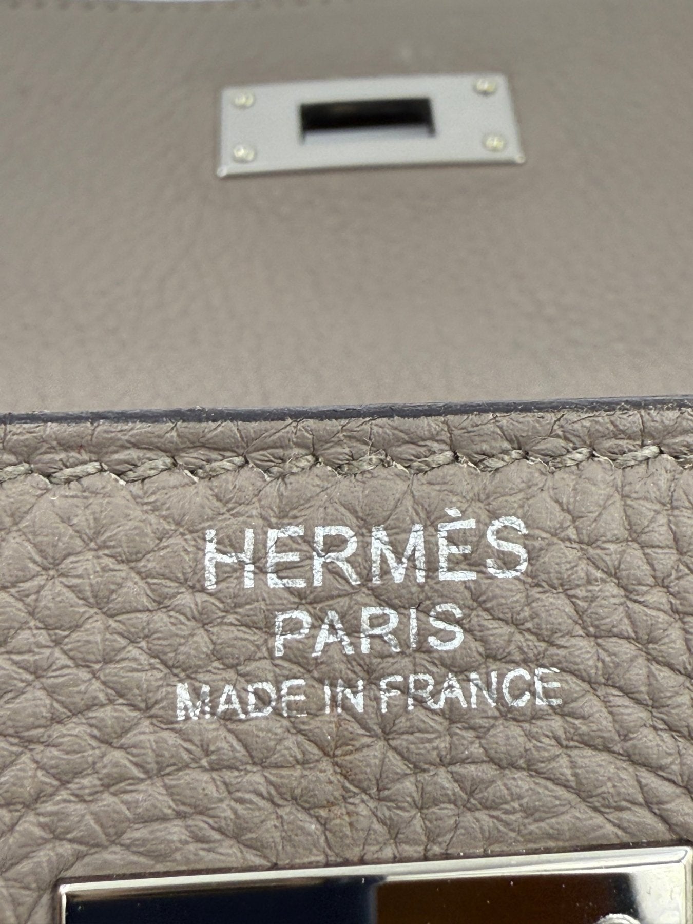 HERMÈS Kelly 32 Retourne Gris Asphalte PHW Detailaufnahme des hochwertigen Clemence Leders mit Prägung Made in France.