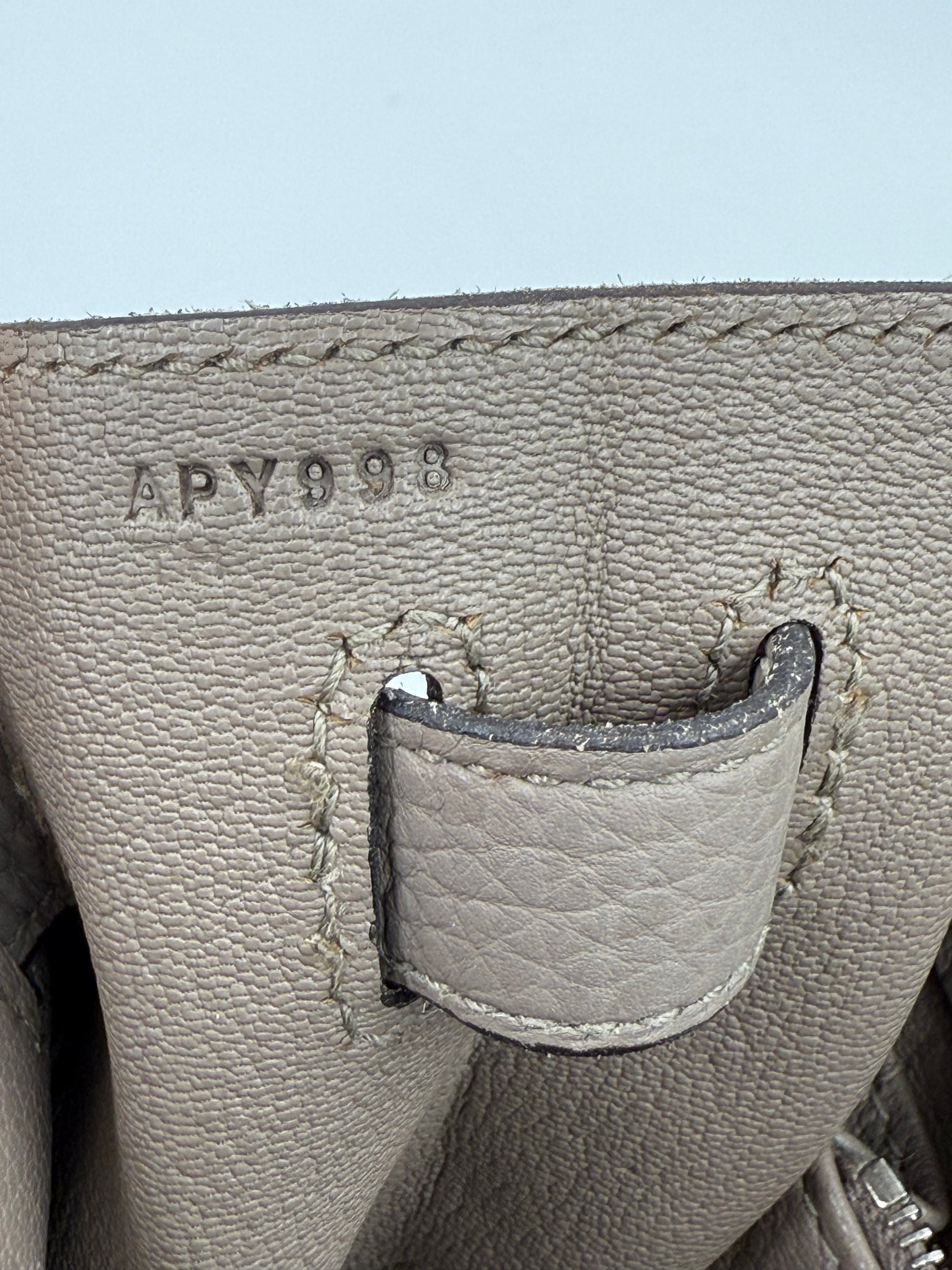 HERMÈS Kelly 32 Retourne Gris Asphalte PHW Nahaufnahme der Lederprägung und Nahtdetails in elegantem Grau.
