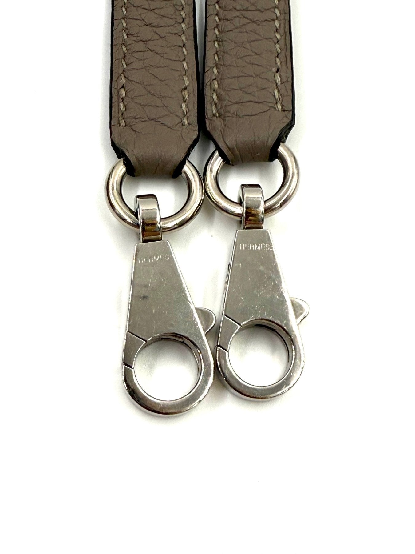 HERMÈS Kelly 32 Retourne Gris Asphalte PHW Lederriemen mit Palladium-Hardware und HERMÈS Gravur, Nahaufnahme.