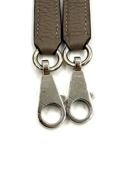 HERMÈS Kelly 32 Retourne Gris Asphalte PHW Lederriemen mit Palladium-Hardware und HERMÈS Gravur, Nahaufnahme.