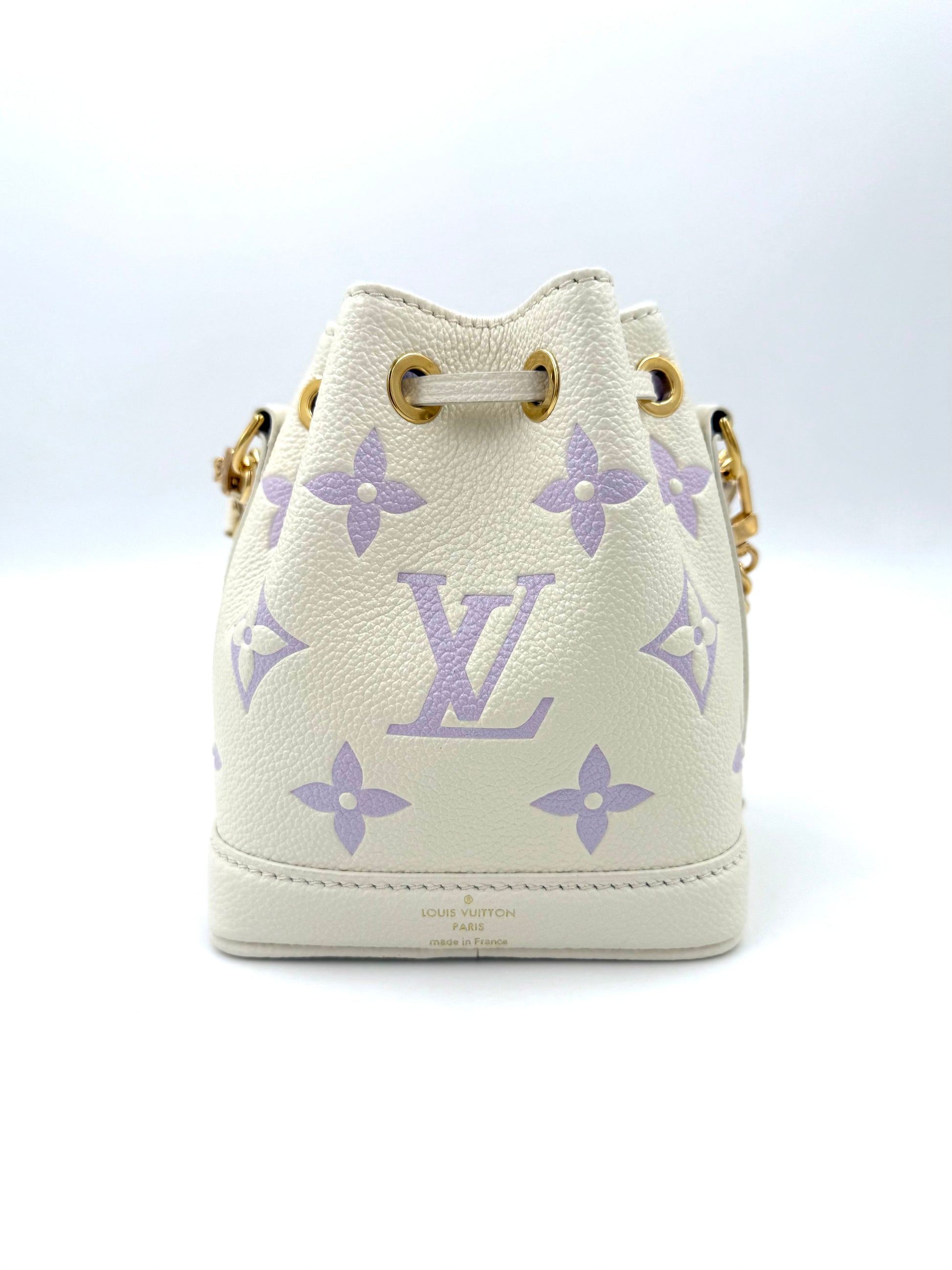 LOUIS VUITTON Nano Noe Monogram Empreinte creme-flieder Handtasche mit goldfarbener Hardware und verstellbarem Schulterriemen.