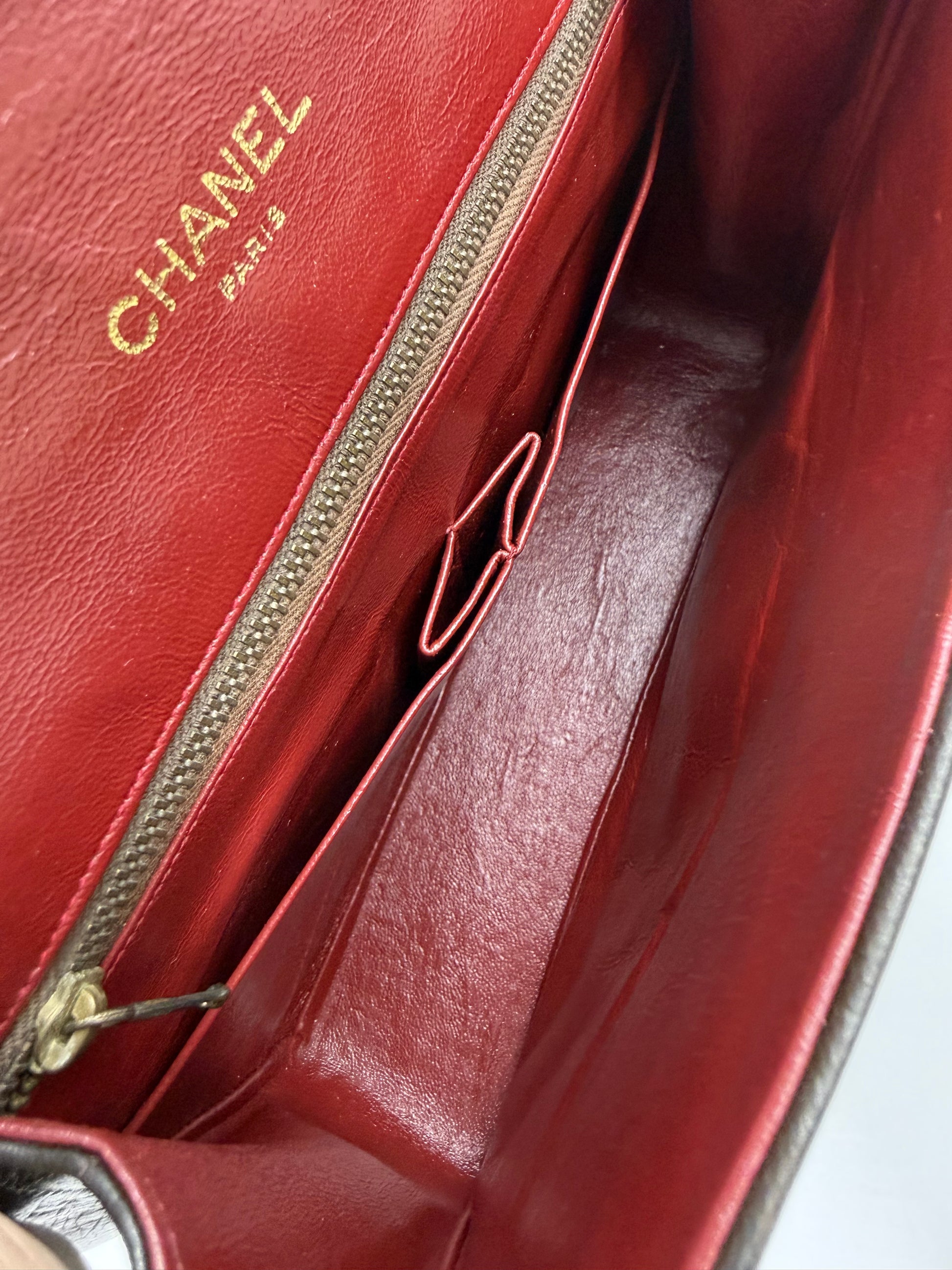 CHANEL Single Flap Lammleder schwarz GHW Nahaufnahme des roten Innenfutters mit Markenprägung und Reißverschlusstasche