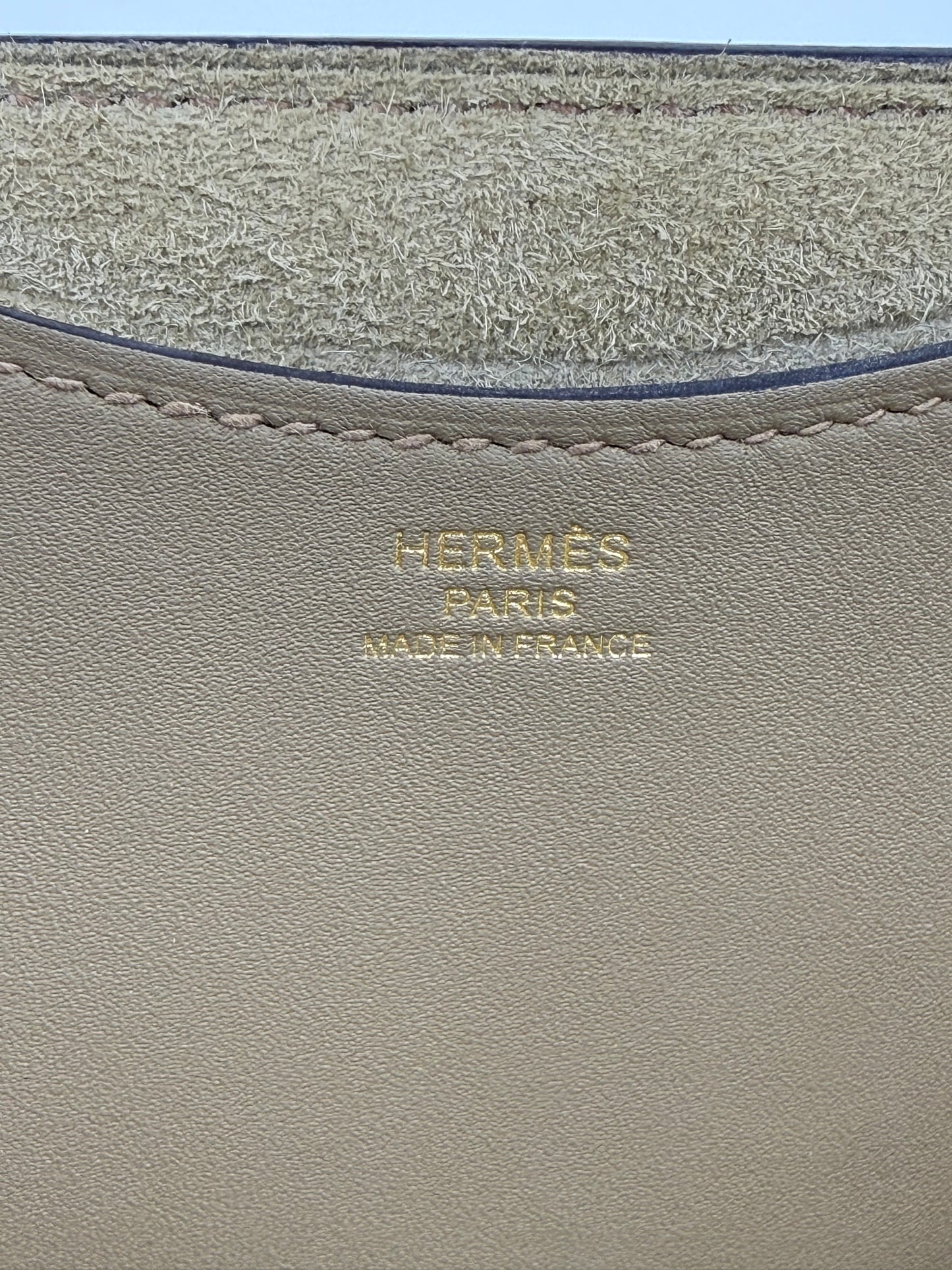 HERMÈS Loop 18 Sauge Detailansicht des goldfarbenen Logos und der feinen Naht auf geschmeidigem Leder in Salbeigrün