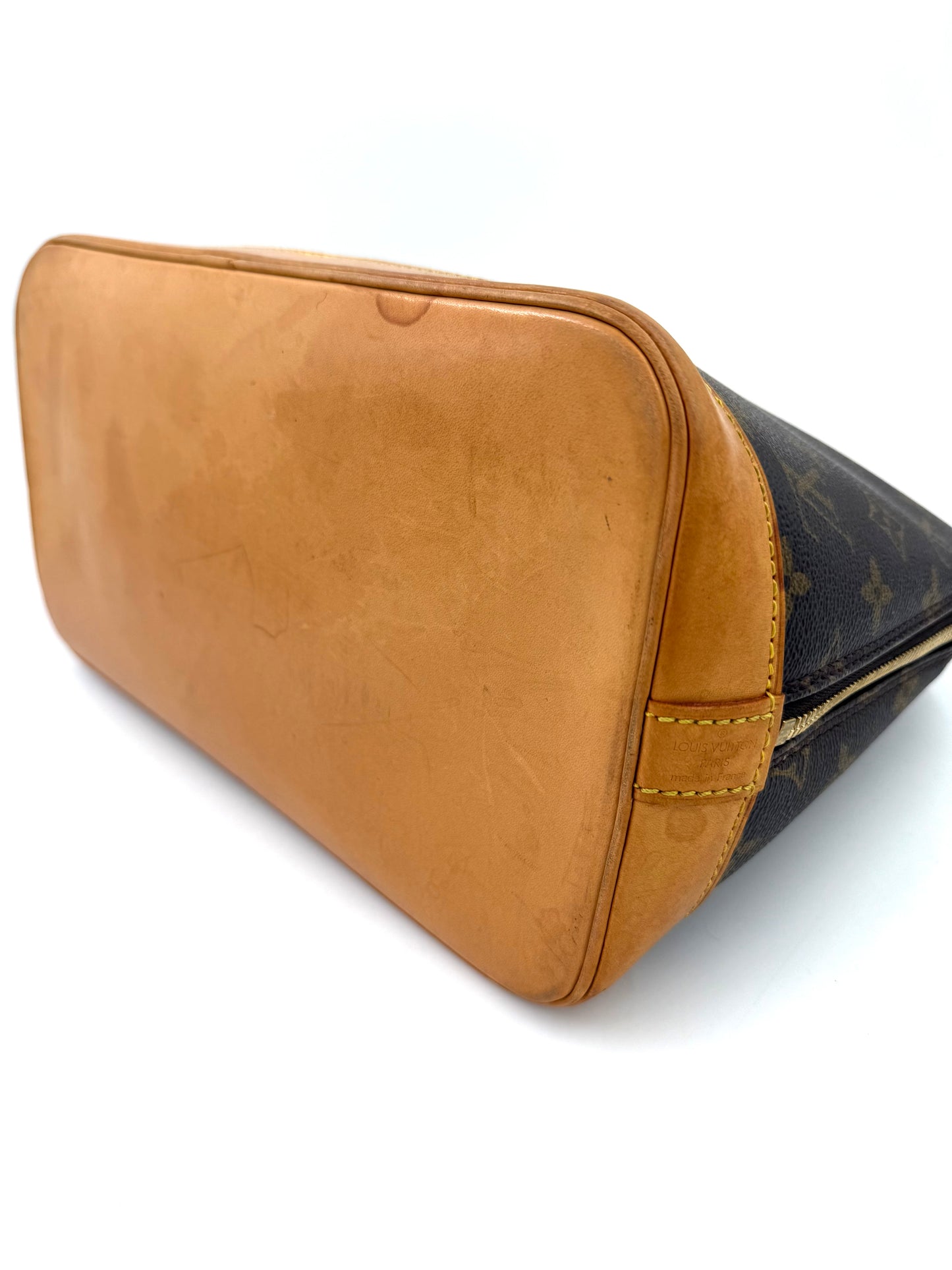 LOUIS VUITTON Alma PM Monogram Canvas Nahaufnahme des braunen Lederbodens mit sichtbaren Gebrauchsspuren