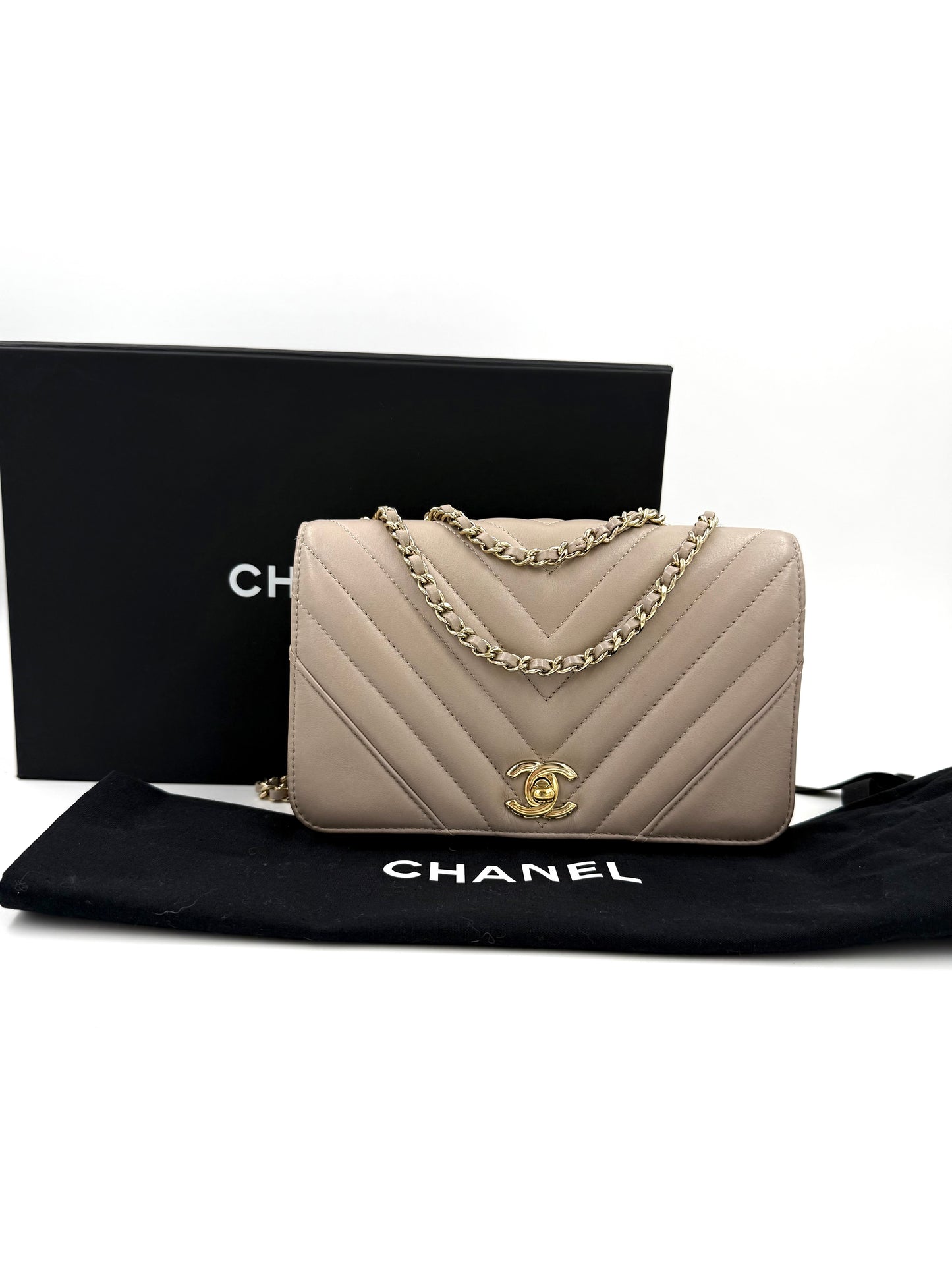 CHANEL Timeless Single Flap Bag Chevron taupe GHW mit goldfarbenem Doppel-C Verschluss und Kettenriemen auf schwarzem Untergrund