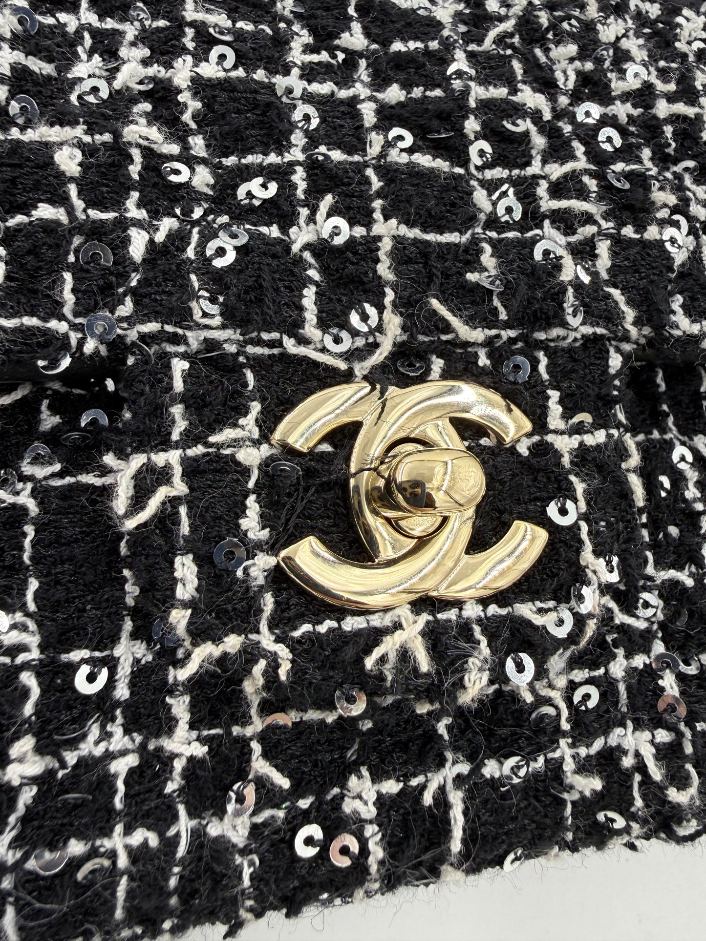 CHANEL Flap Bag Tweed schwarz/weiß GHW mit goldfarbenem Verschluss und eleganter Paillettenverzierung aus Tweedstoff.