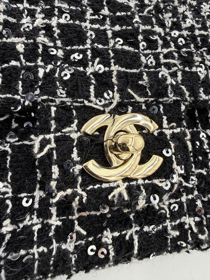 CHANEL Flap Bag Tweed schwarz/weiß GHW mit goldfarbenem Verschluss und eleganter Paillettenverzierung aus Tweedstoff.