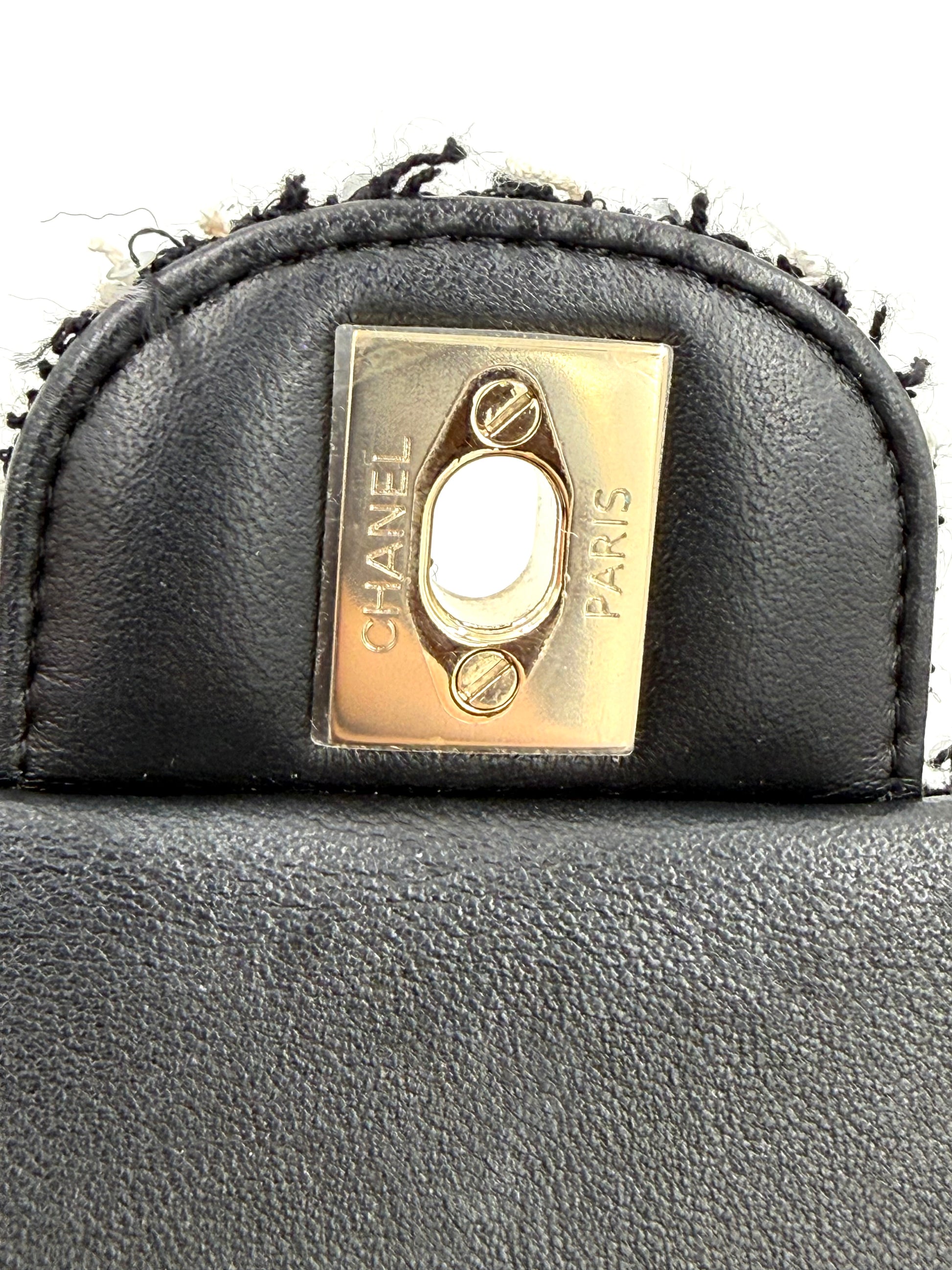 Schließelement mit graviertem CHANEL Flap Bag Tweed schwarz/weiß GHW Logo in schwarzem Lederimitat.