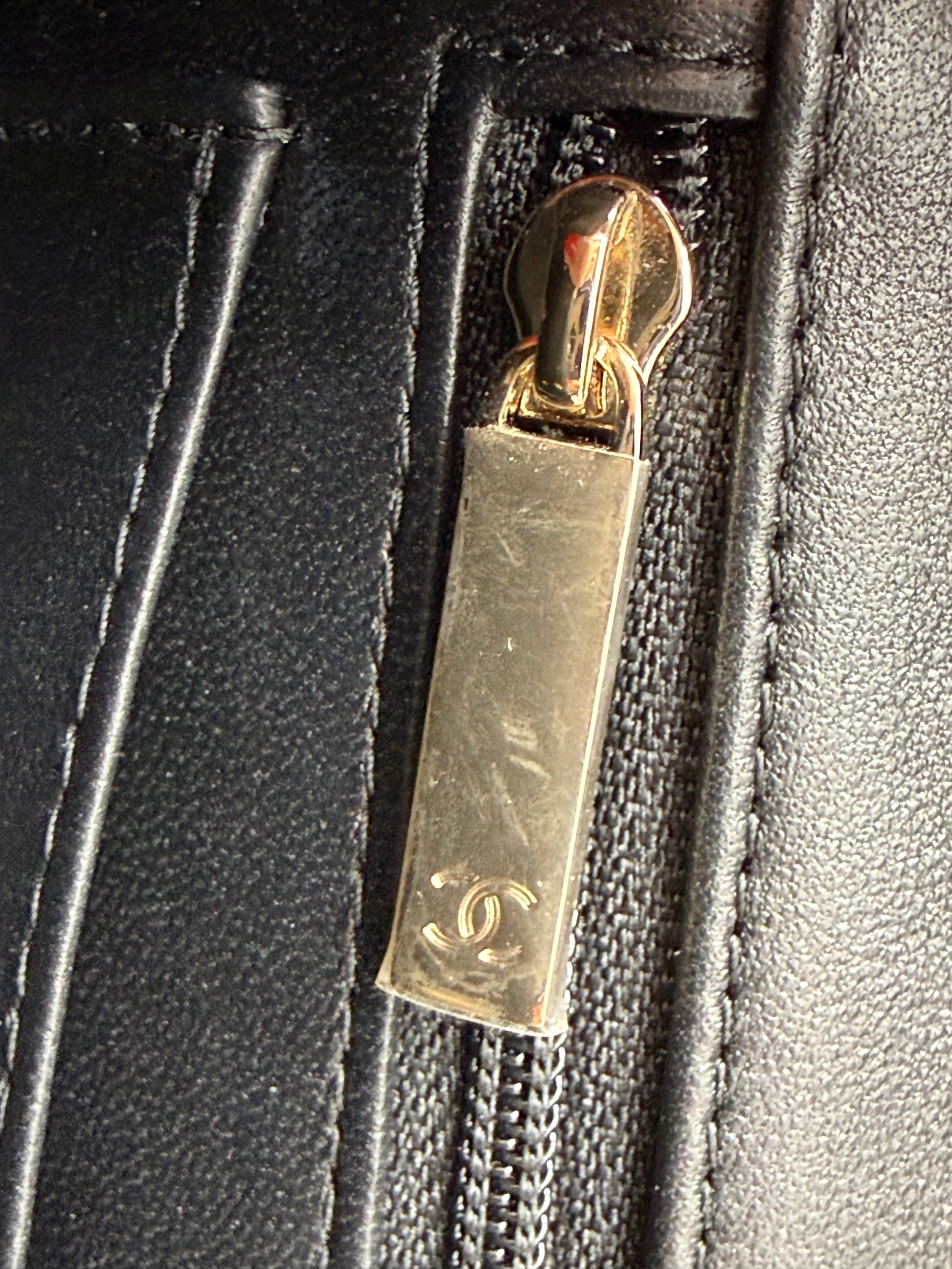 Detailaufnahme eines Reißverschlusses mit goldfarbenem Anhänger an der CHANEL Flap Bag Tweed schwarz/weiß GHW.