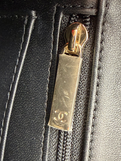Detailaufnahme eines Reißverschlusses mit goldfarbenem Anhänger an der CHANEL Flap Bag Tweed schwarz/weiß GHW.