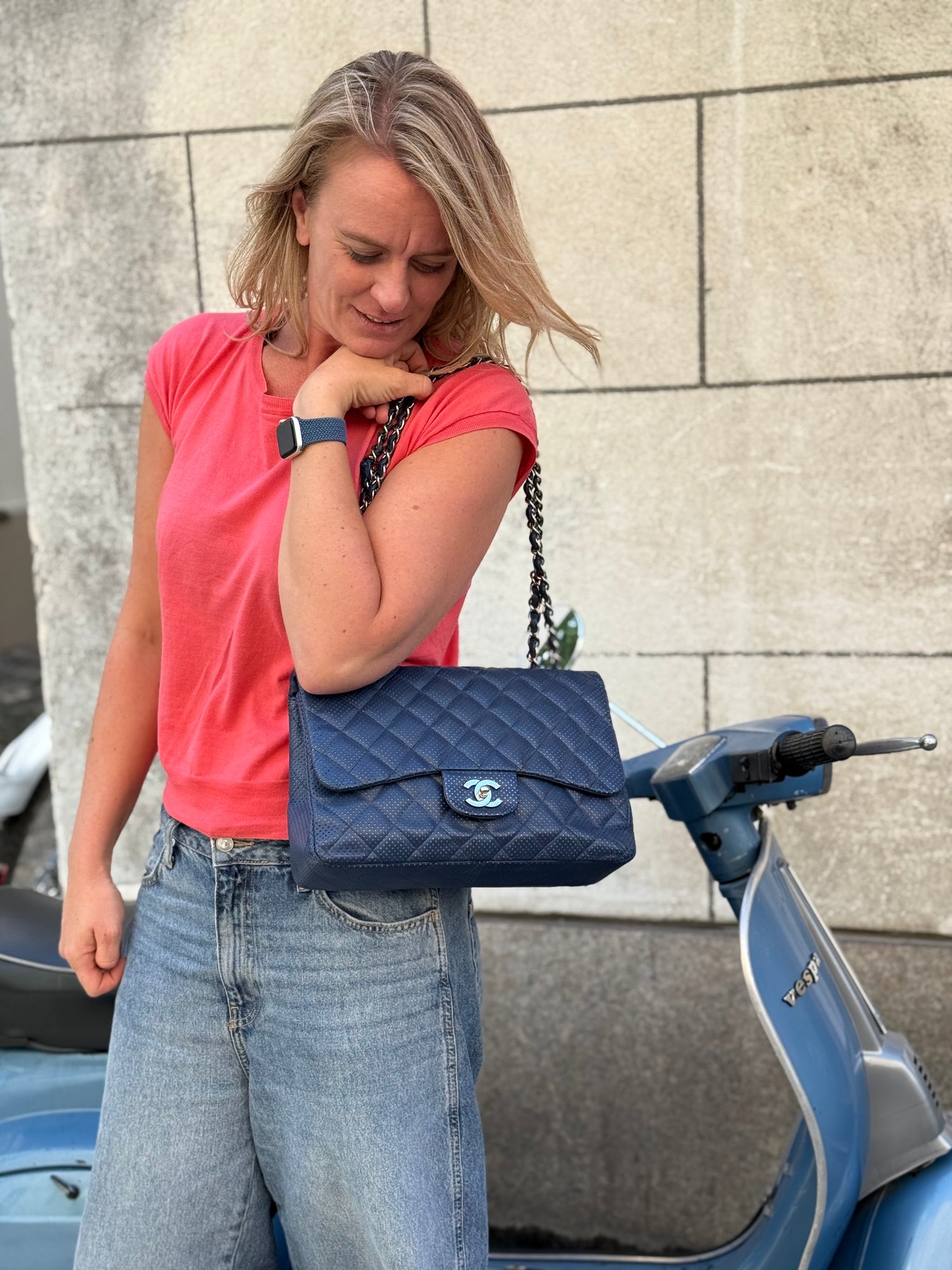 Frau mit dunkelblauer gesteppter CHANEL Handtasche neben einem Motorroller
