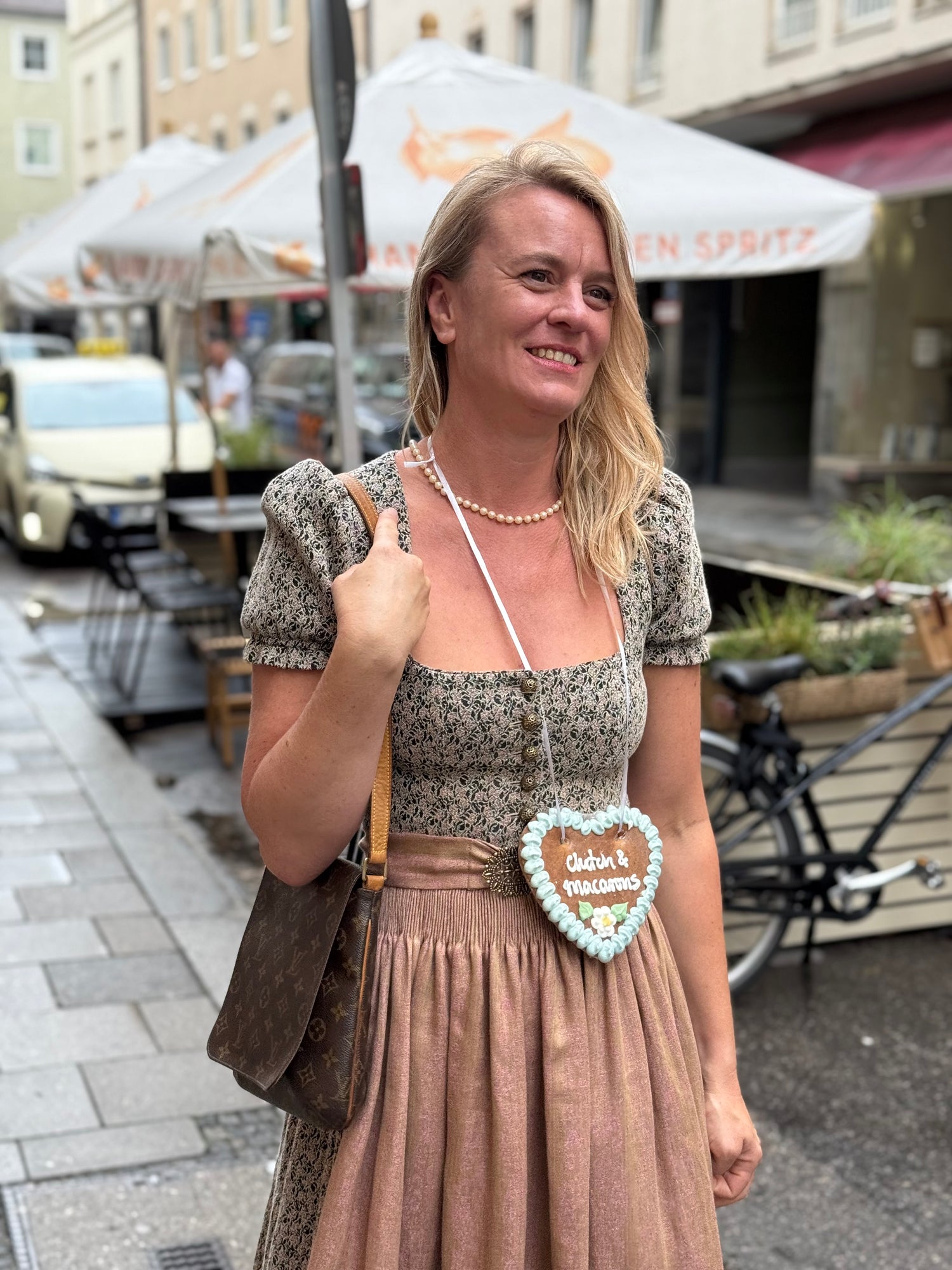 Frau in traditioneller Tracht mit brauner Schultertasche auf einer belebten Münchner Straße