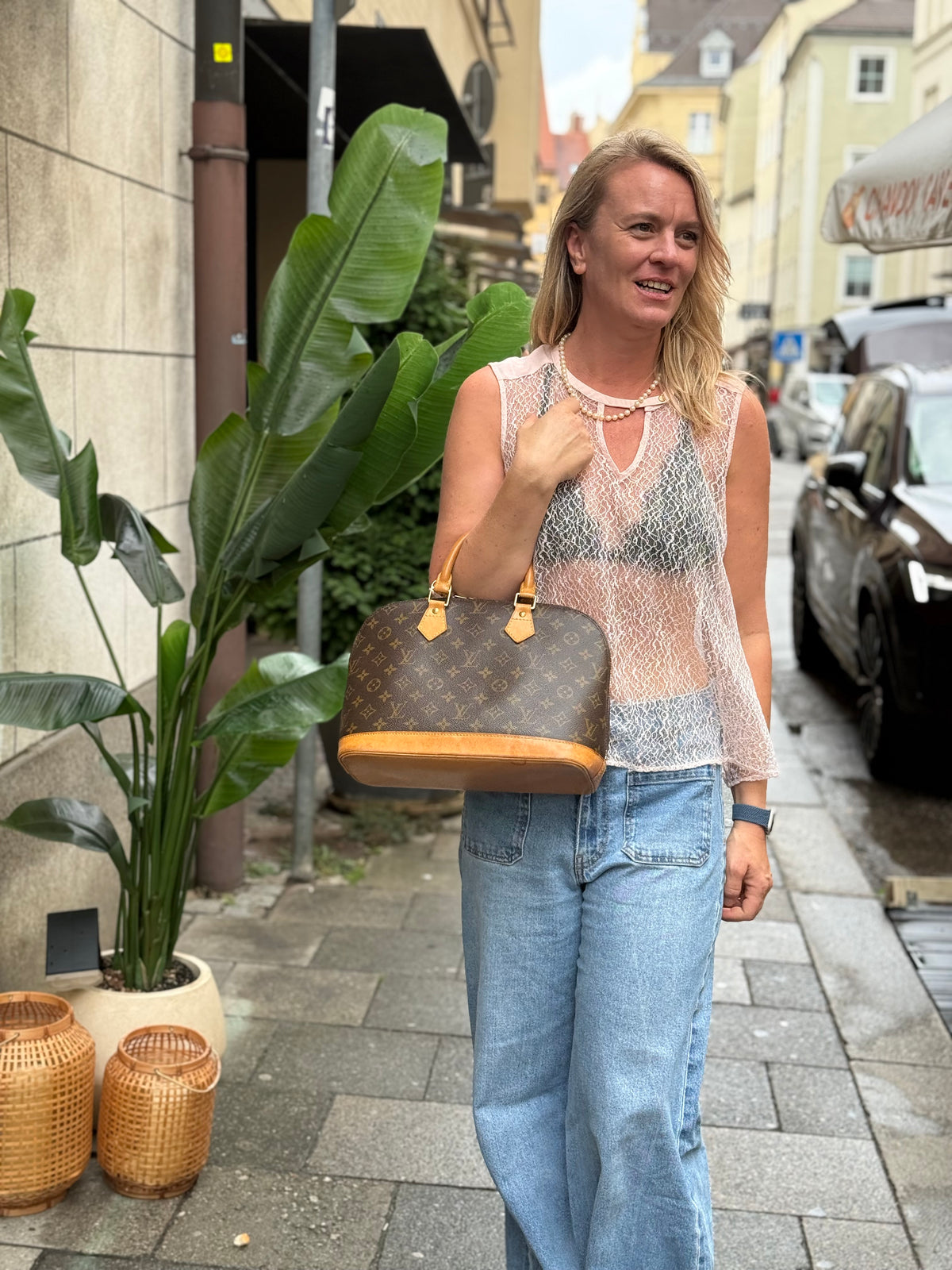 Frau trägt eine braune Louis-Vuitton-Handtasche in einer Münchner Altstadtgasse