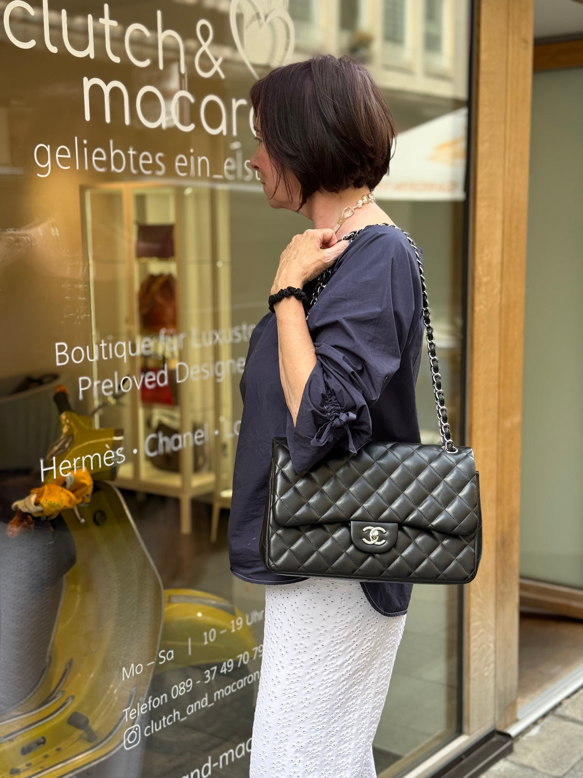 Frau mit schwarzer gesteppter Chanel-Handtasche vor einer Boutique in München