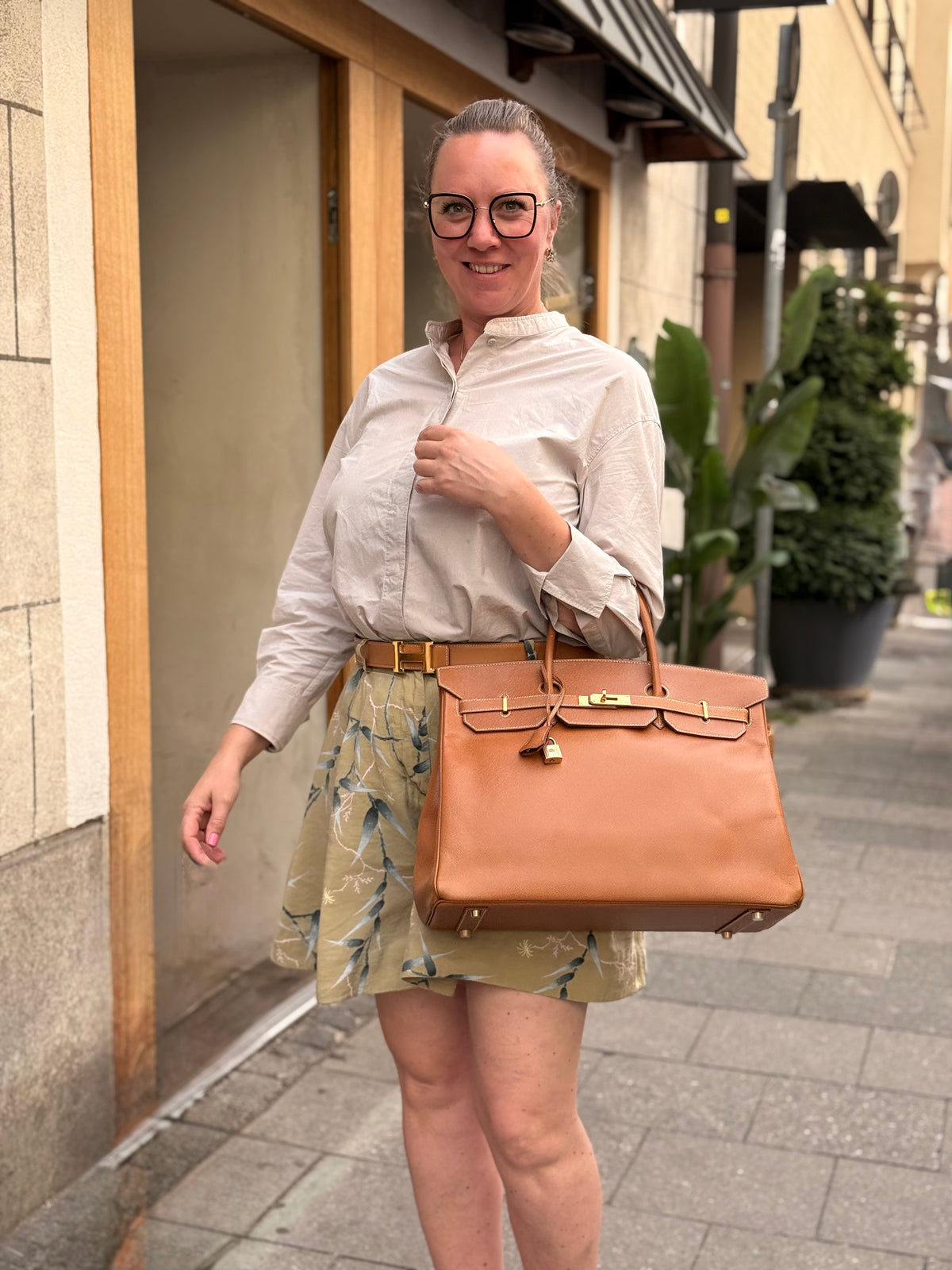 Frau mit großer cognacfarbener Handtasche vor einem Hauseingang