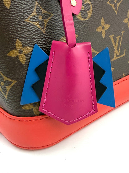 Nahaufnahme der LOUIS VUITTON Alma BB Love Birds mit Detail von pinkem Lederanhänger und blau-schwarzem Dekor.