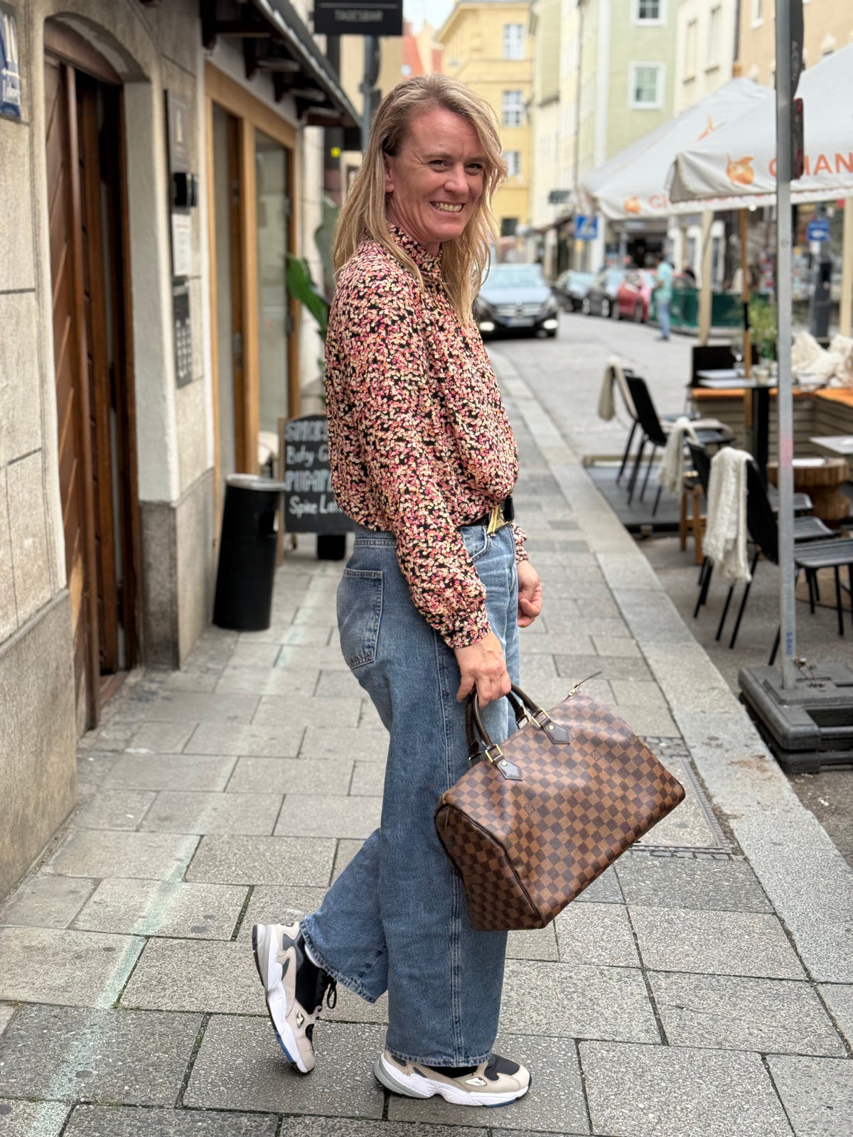 Frau mit brauner karierter Handtasche in einer Altstadtgasse