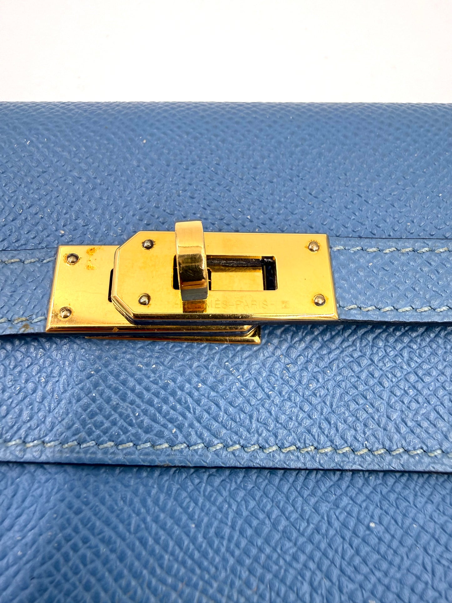 HERMÈS Kelly long Wallet Epsom Bleu Izmir GHW Detail des goldfarbenen Drehverschlusses auf blau genarbtem Leder