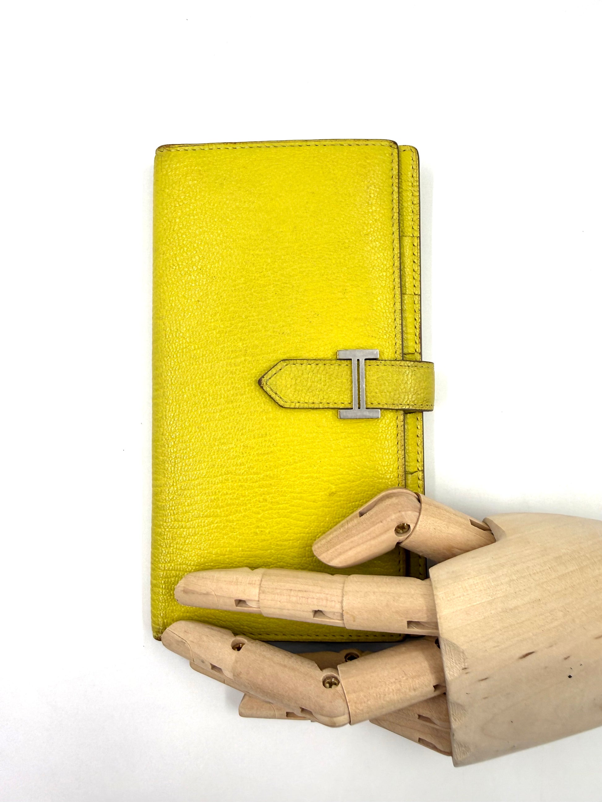 HERMÈS Bearn Wallet Mysoreleder Lime PHW in leuchtendem Gelb mit silberner Schließe, präsentiert von Holzhandmodell.