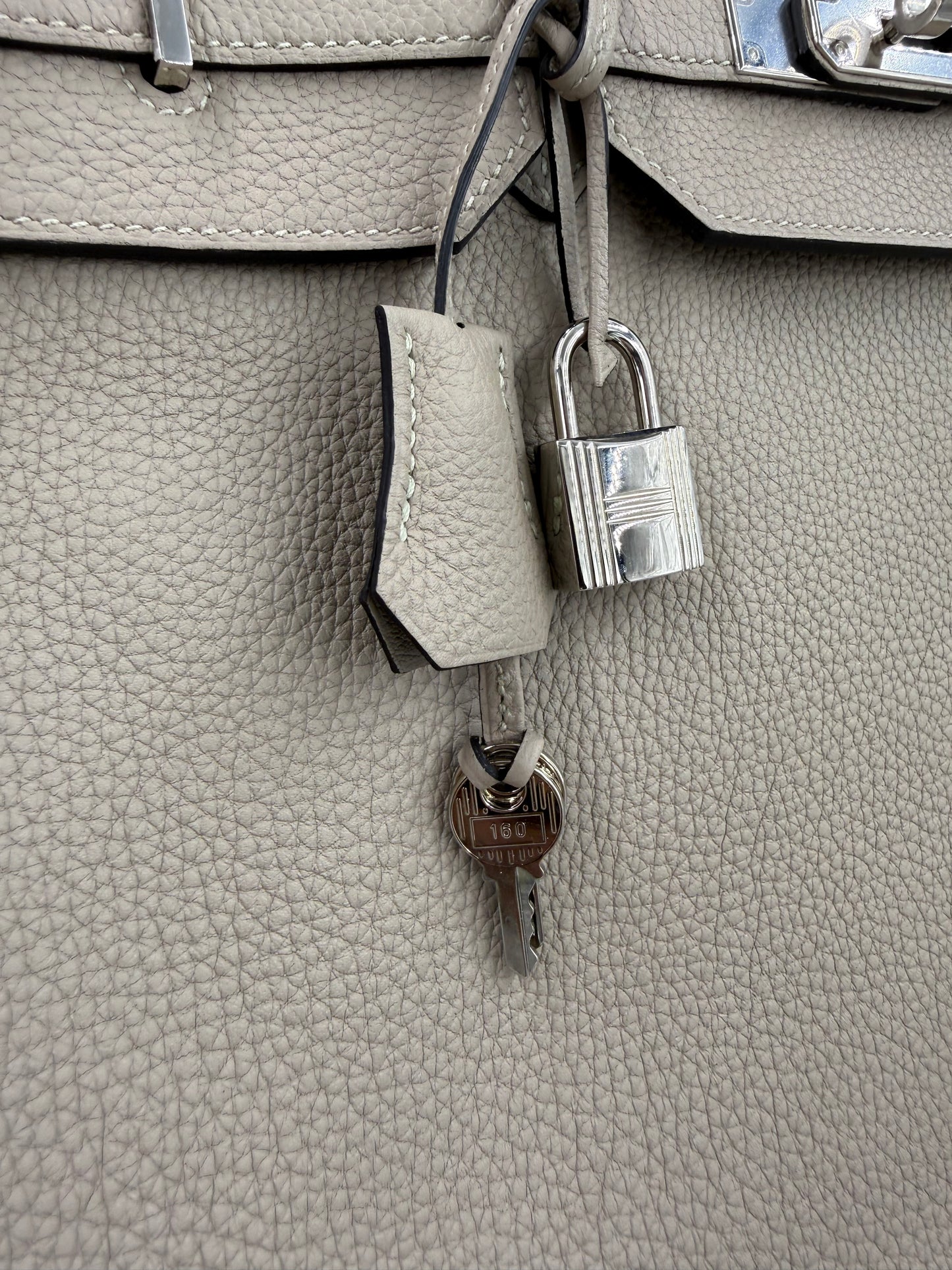 Detailaufnahme des HERMÈS Birkin 40 Togo Gris Tourterelle PHW mit Schloss und Schlüssel aus silberfarbenem Metall.