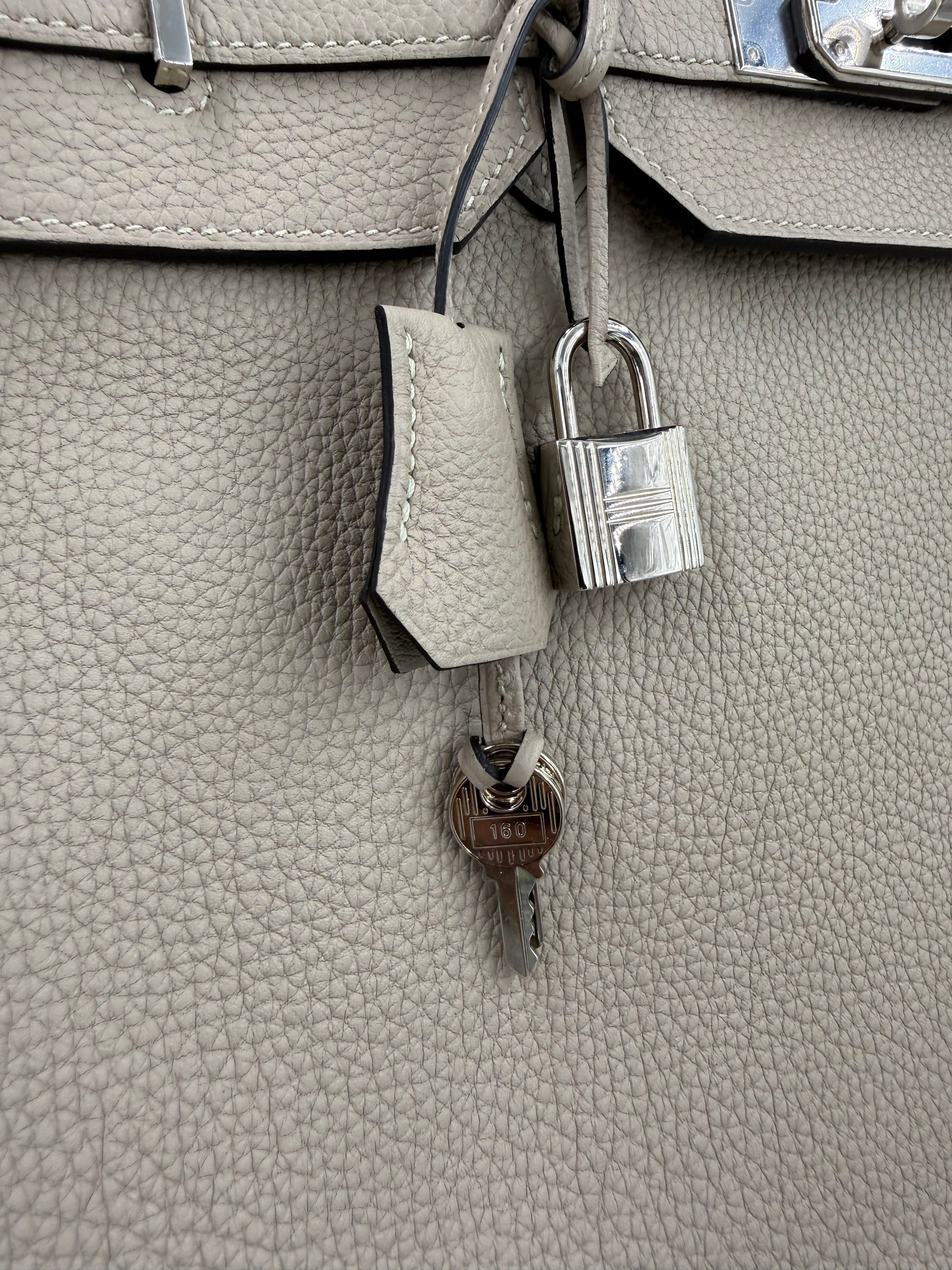 Detailaufnahme des HERMÈS Birkin 40 Togo Gris Tourterelle PHW mit Schloss und Schlüssel aus silberfarbenem Metall.