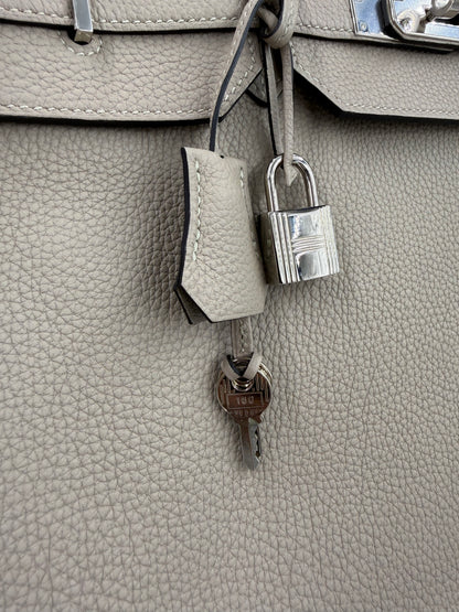 Detailaufnahme des HERMÈS Birkin 40 Togo Gris Tourterelle PHW mit Schloss und Schlüssel aus silberfarbenem Metall.