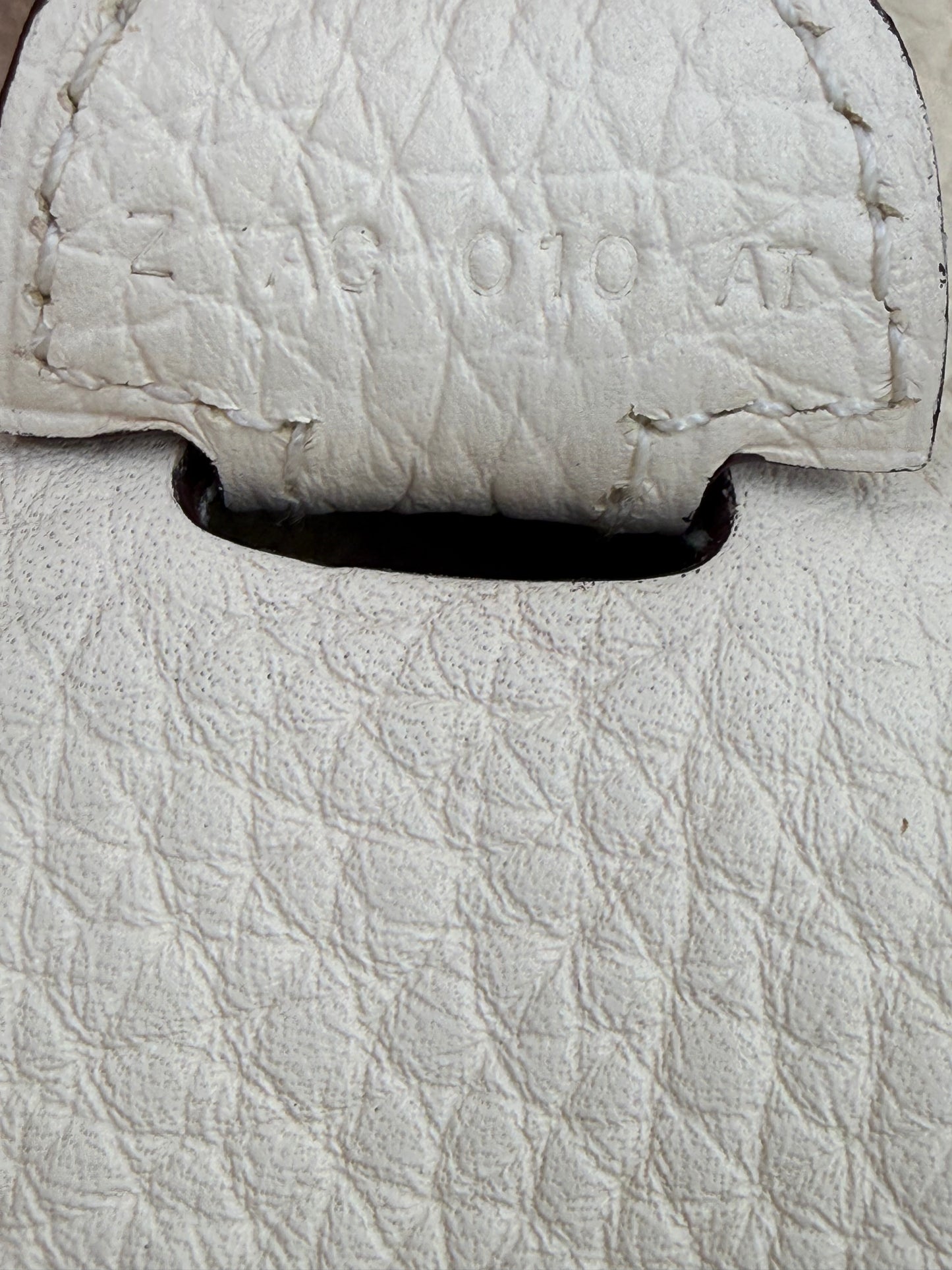 Nahaufnahme der weißen Prägung auf HERMÈS Evelyne 29 Nata Clemence PHW Lederstruktur der Handtasche.