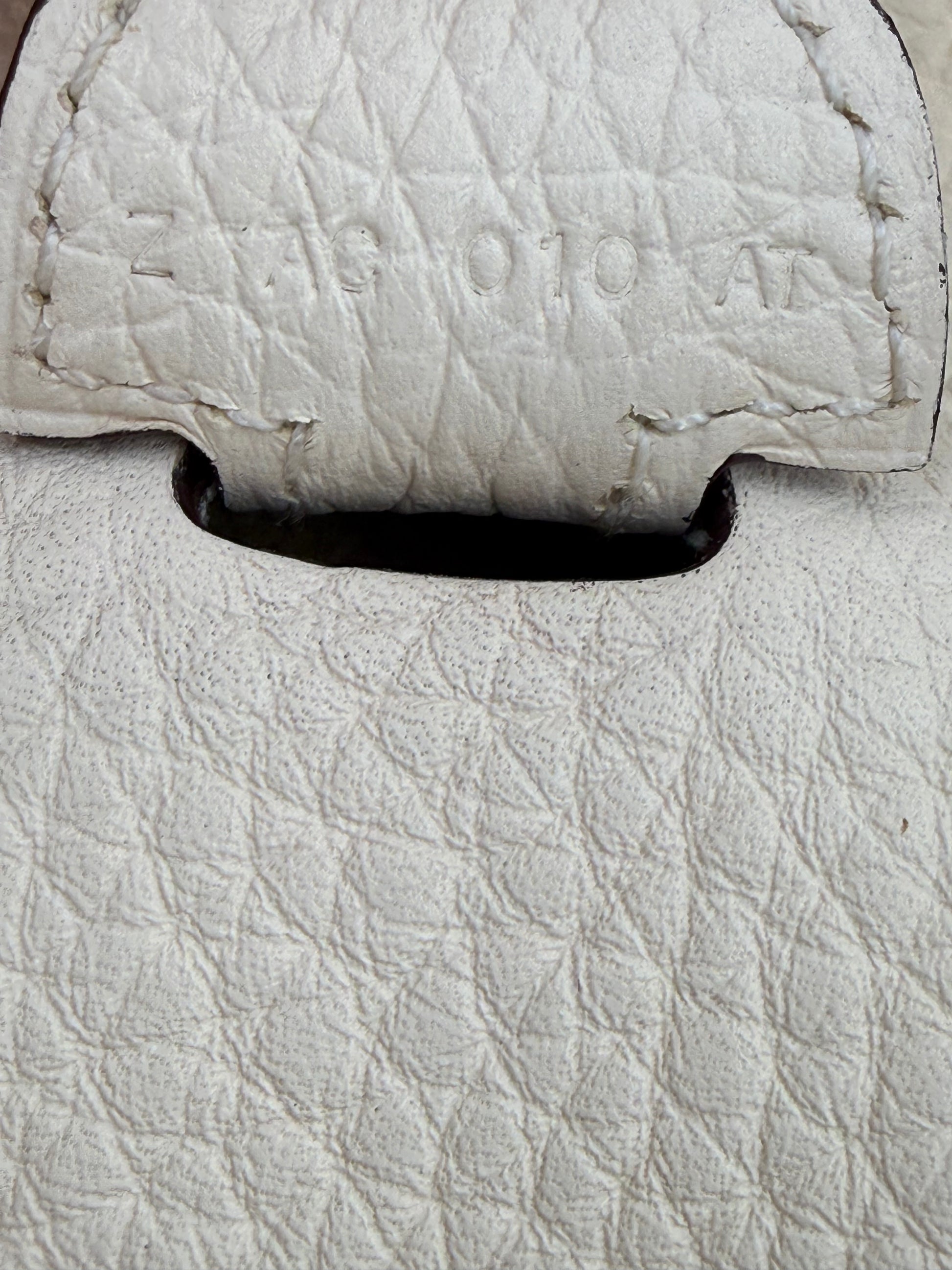 Nahaufnahme der weißen Prägung auf HERMÈS Evelyne 29 Nata Clemence PHW Lederstruktur der Handtasche.