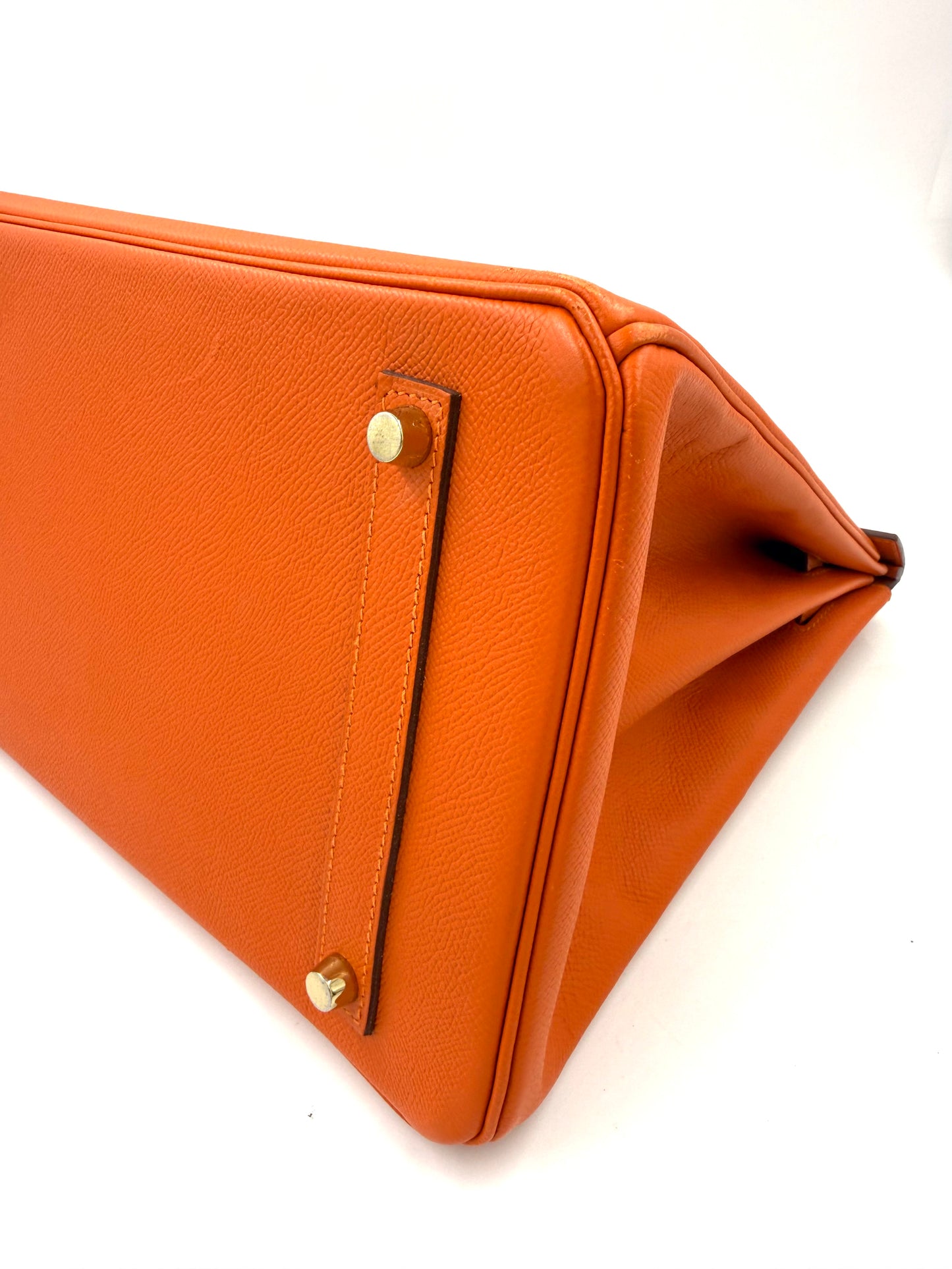 HERMÈS Birkin 35 Epsom orange GHW Nahaufnahme der Tasche mit sichtbaren goldfarbenen Metallfüßen und feinem Narbenleder