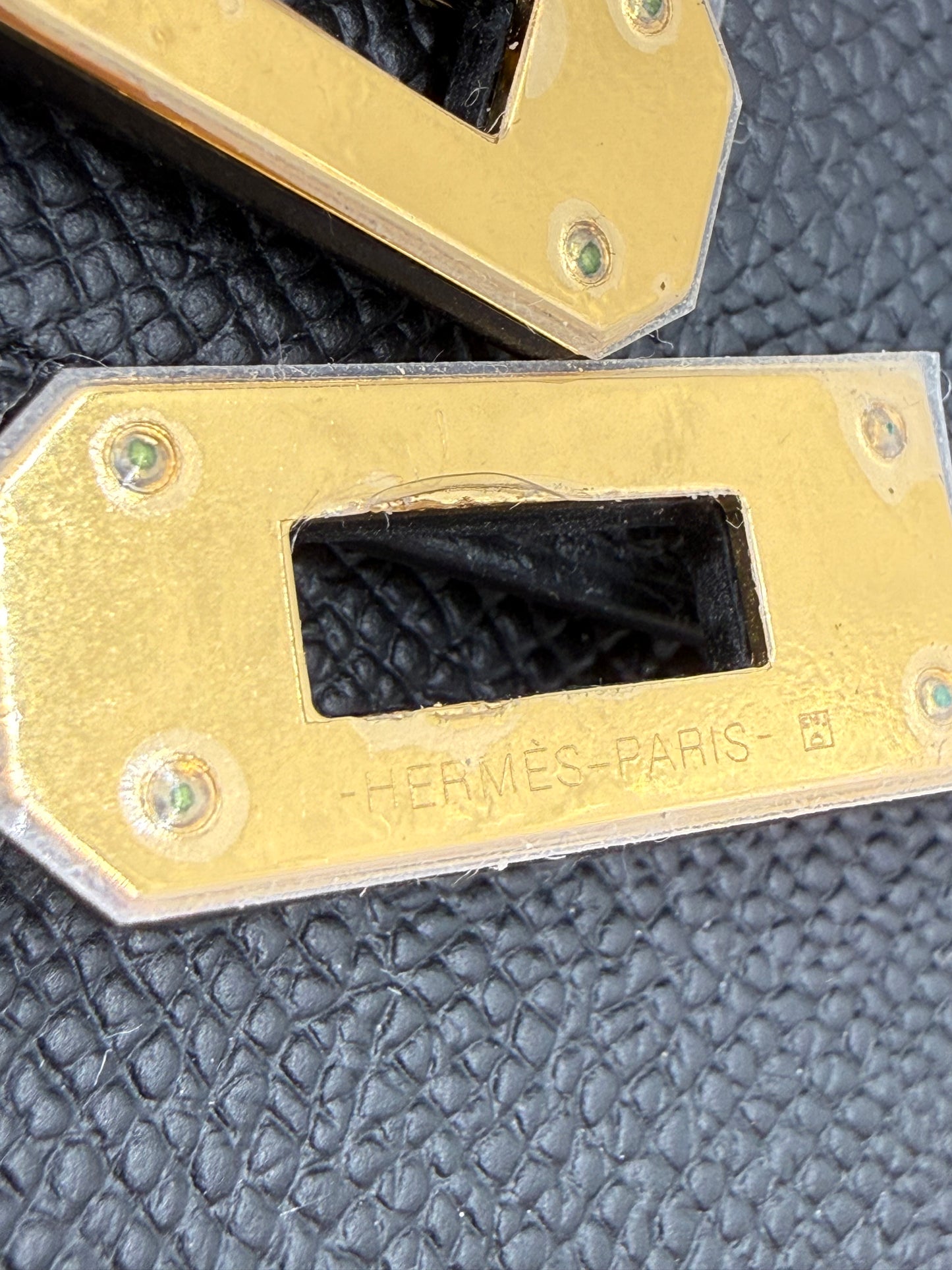 HERMÈS Kelly to Go Epsom schwarz GHW Detailaufnahme des goldfarbenen Verschlusses mit geprägtem Hermès Paris Logo