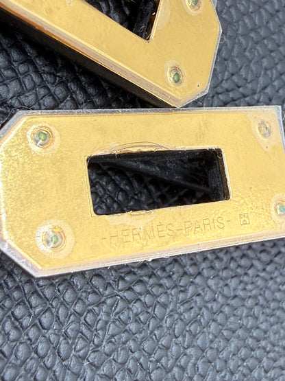 HERMÈS Kelly to Go Epsom schwarz GHW Detailaufnahme des goldfarbenen Verschlusses mit geprägtem Hermès Paris Logo